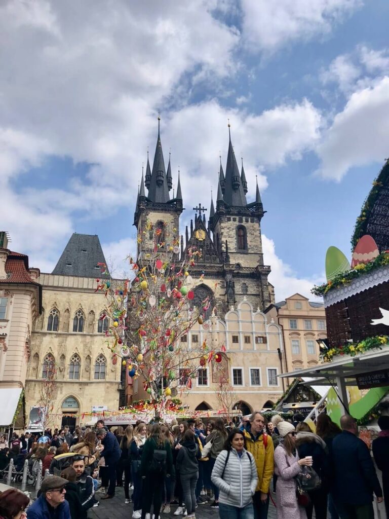 A festive Easter market fills Prague’s Old Town Square, with an Easter tree decorated with colorful eggs and ribbons. The gothic towers of the Church of Our Lady before Týn create a striking backdrop against the lively crowd.